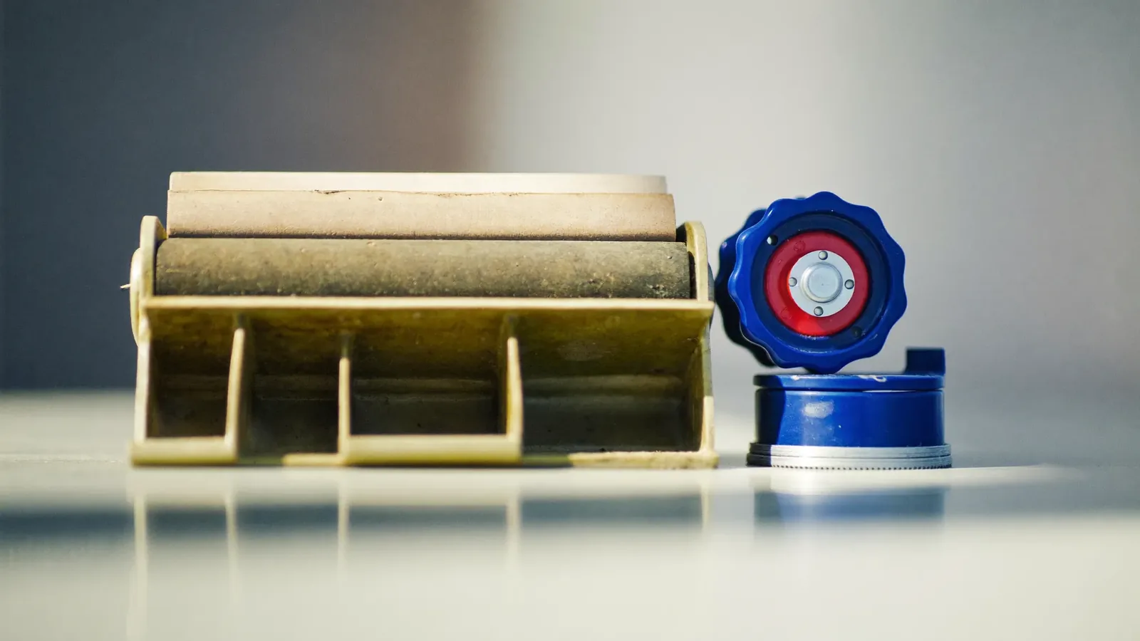 A worn sliding door roller with a flattened wheel next to a clean replacement