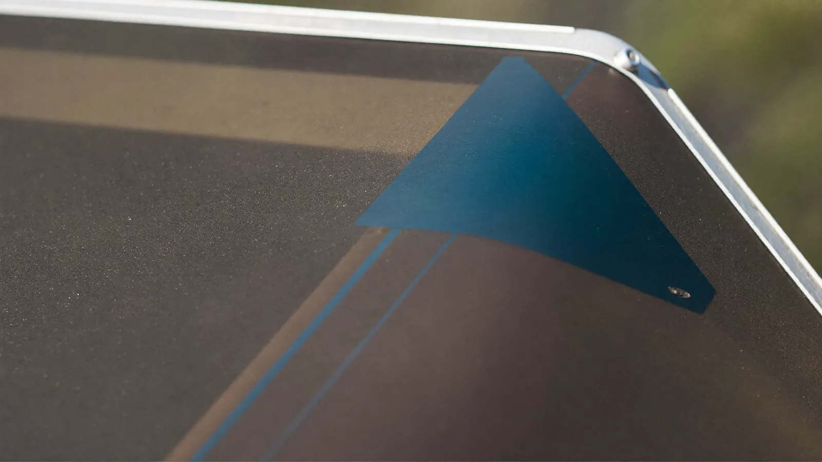 Corner of a solar-control glass pane showing the blue-green tint of its coated surface