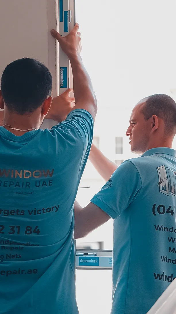 Two technicians aligning a new window frame in a Dubai apartment