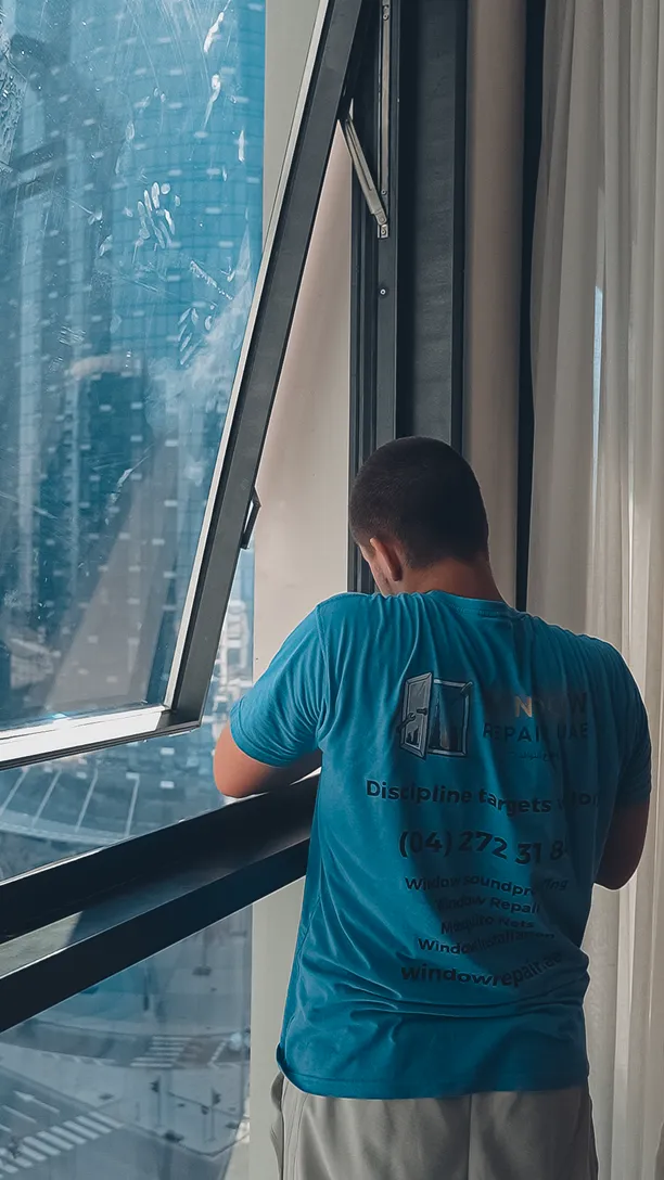 Technician working on an open sash with Dubai towers behind the glass