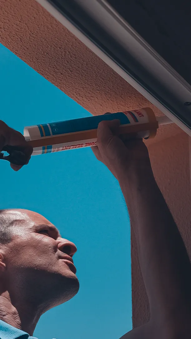 Technician sealing the head of a window opening from below
