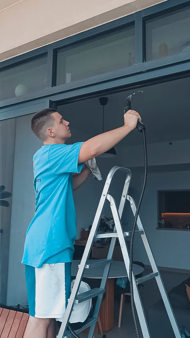 Technician on a step ladder servicing the top of the glazing