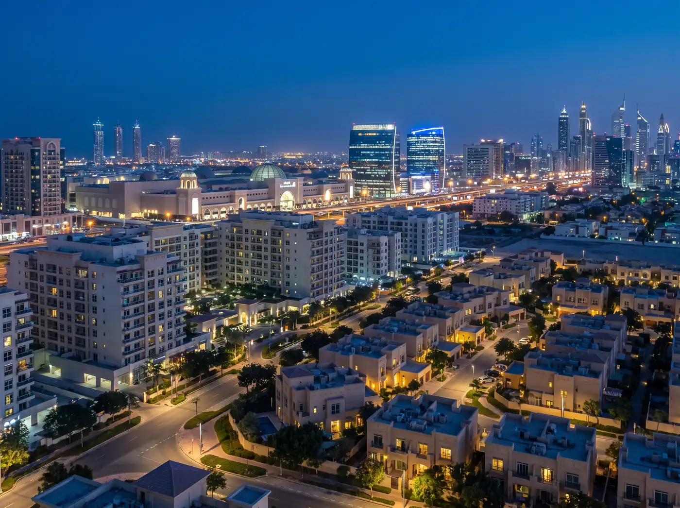Al Barsha district at blue hour: villas and mid-rise buildings with the Sheikh Zayed Road skyline behind