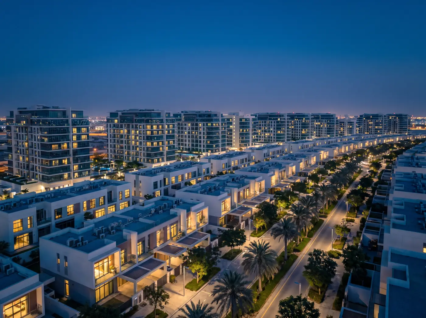 Al Furjan at dusk: modern townhouses and mid-rise buildings on tree-lined streets