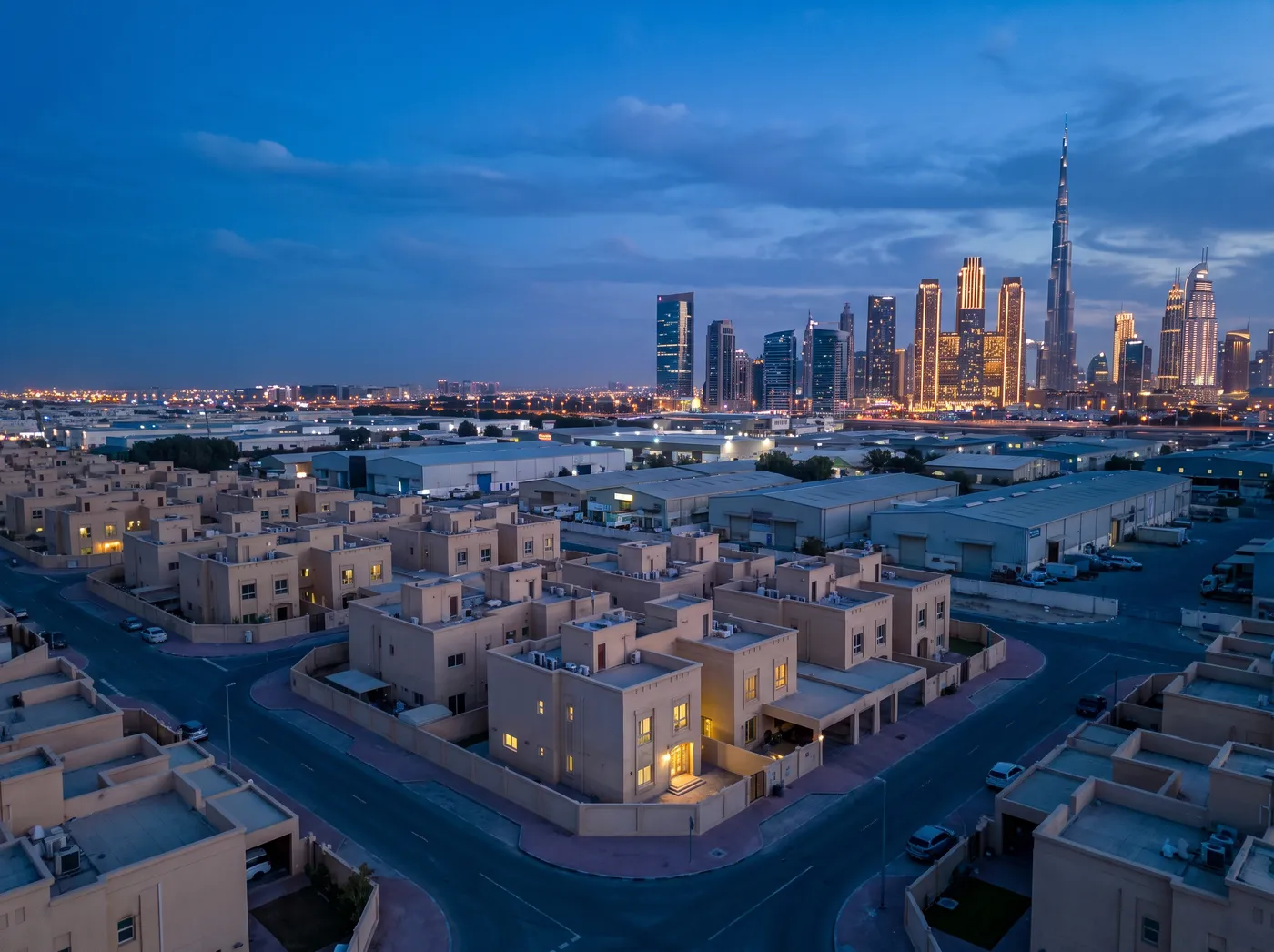 Al Quoz at dusk: villas and low warehouses with the Sheikh Zayed Road towers on the horizon