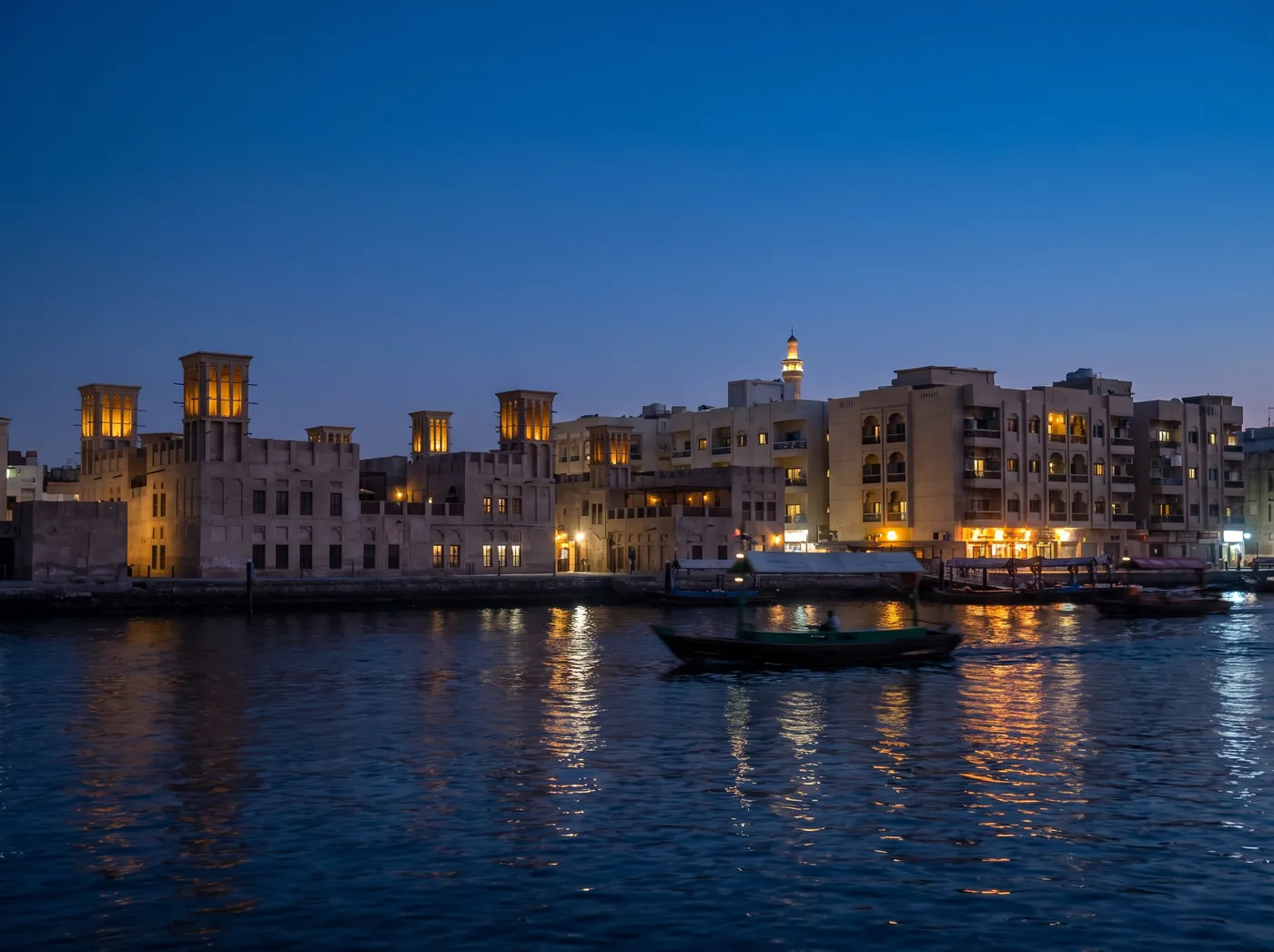 Bur Dubai creek-side blocks at blue hour with abra boats on the water