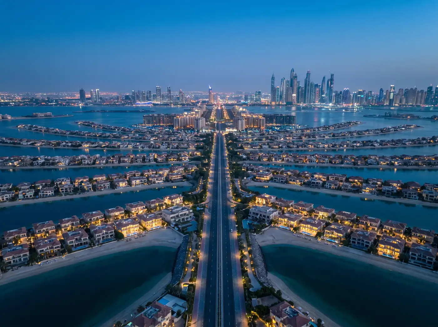 Palm Jumeirah beachfront villas along the fronds at blue hour, Marina skyline across the water