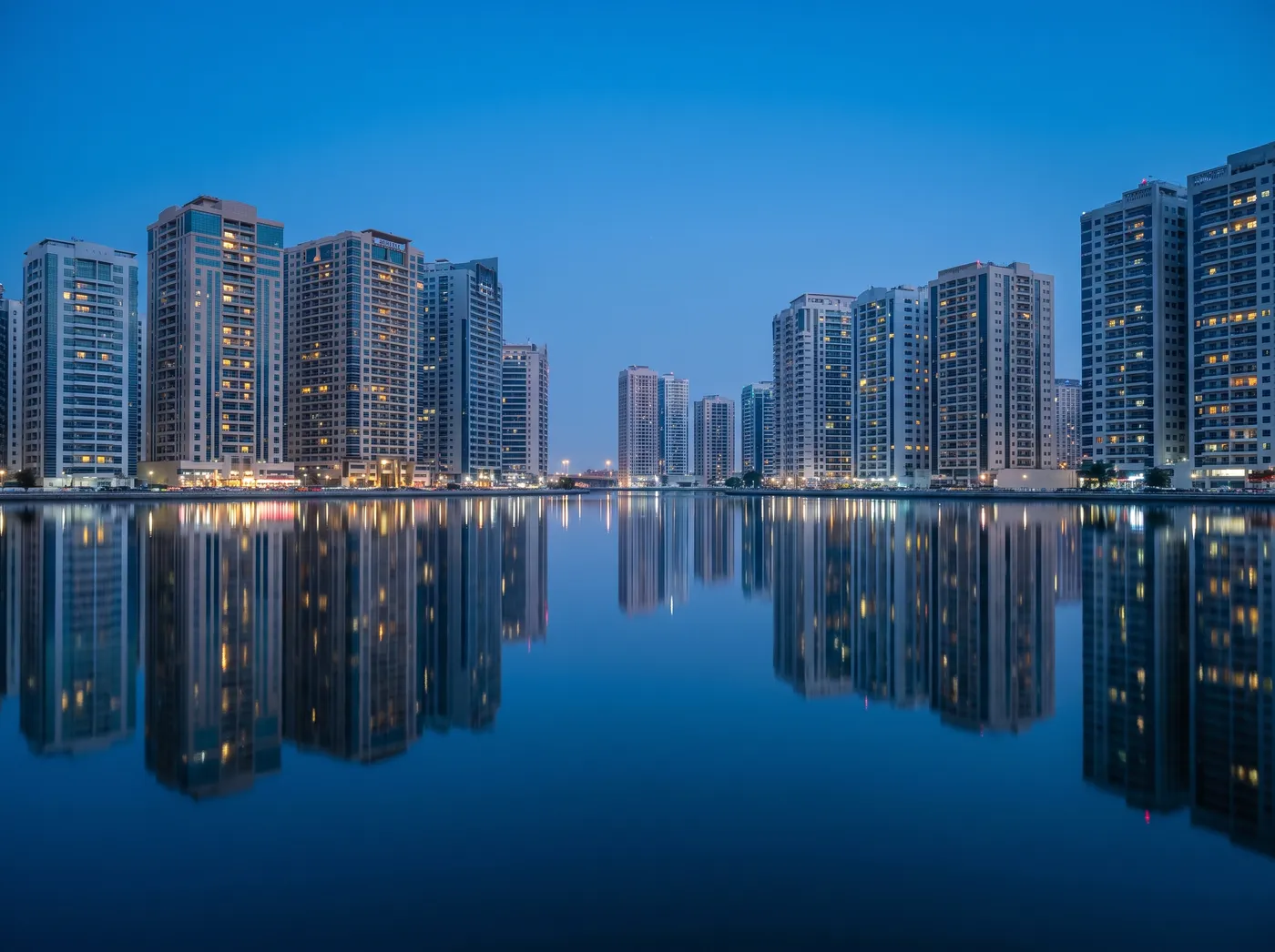 Sharjah residential towers around Khalid Lagoon at blue hour