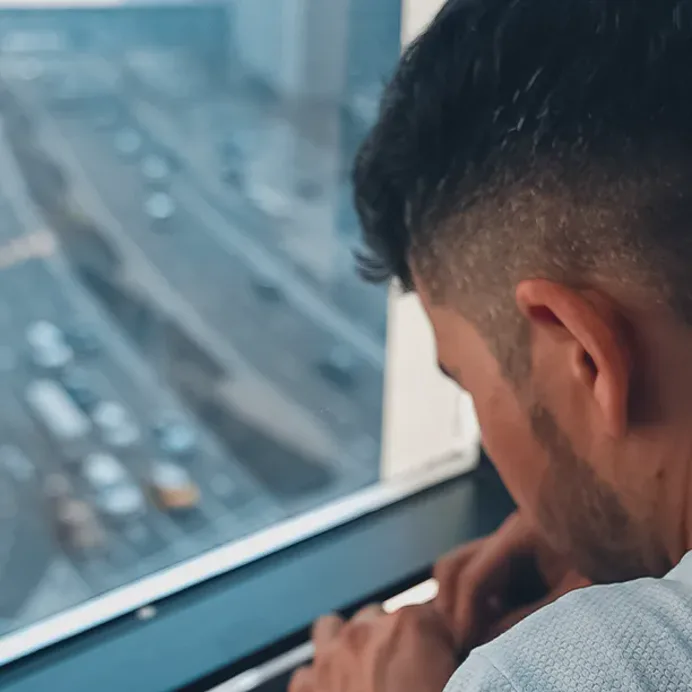 A technician works on a frame at height, the highway far below