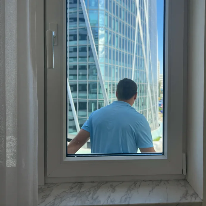 Technician at a white uPVC window, a tower beyond the glass