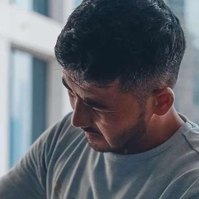 A technician at the glass, daylight from the window across his face
