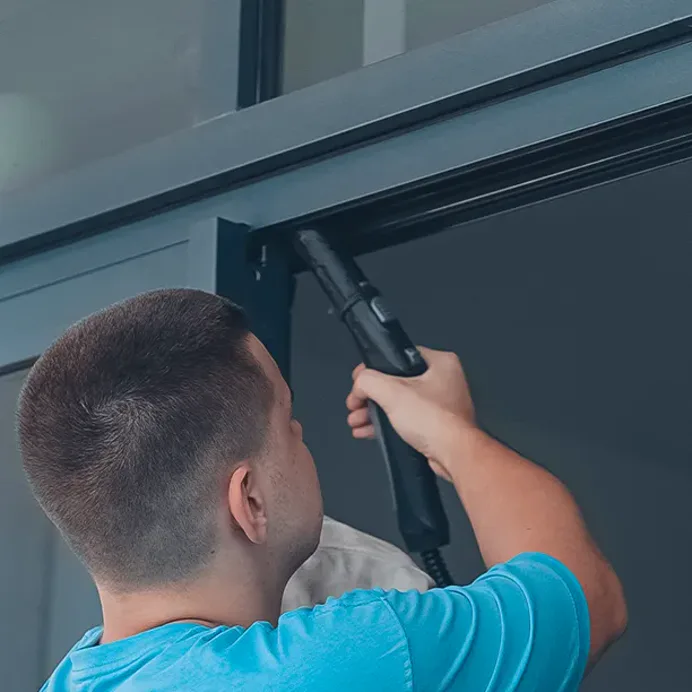 A technician vacuums the head track of a sliding door