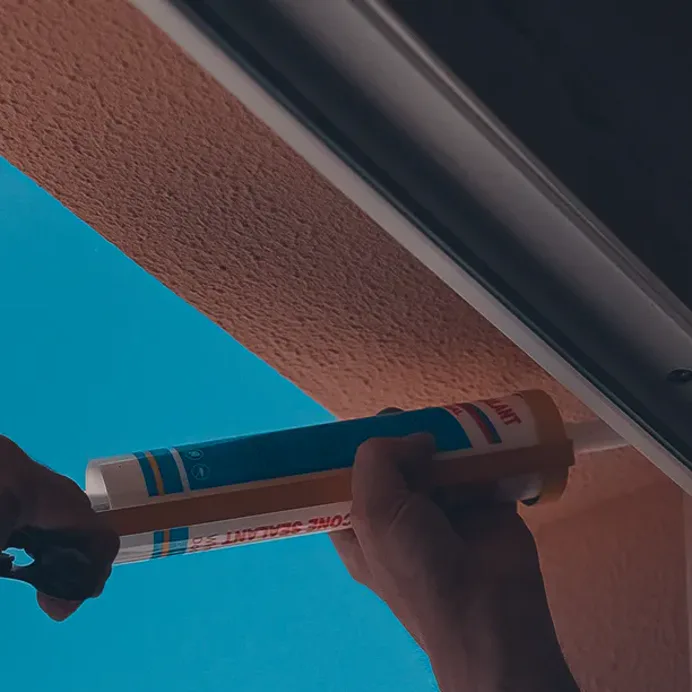 A sealant gun laying a fresh bead along a window reveal